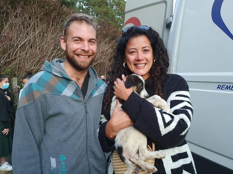 Un couple souriant reçoit son chiot devant le camion de rapatriement Remember Me France